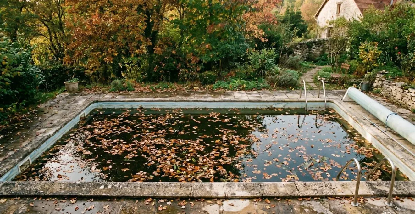 Piscine enterrée avec feuilles mortes et débris végétaux flottant à la surface